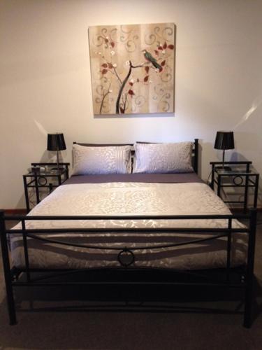 a bed in a bedroom with two lamps and a painting at Mapperley Bed and Breakfast in Bordertown