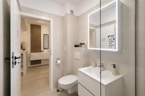 a white bathroom with a toilet and a sink at Sasha Wave Studio in Popeşti-Leordeni