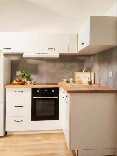 a kitchen with white cabinets and a black oven at OsiedLOVE Poddasze in Jędrzejów