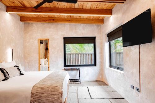 a bedroom with a bed and a flat screen tv at Seabird Villa 3 in Placencia