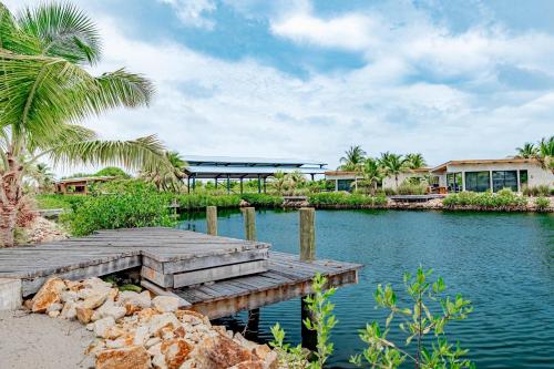a wooden bridge over a body of water with palm trees at Seabird Villa 3 in Placencia