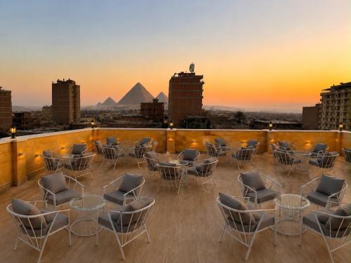 a rooftop deck with chairs and tables and the pyramids at Royal Pyramids Hotel in Cairo