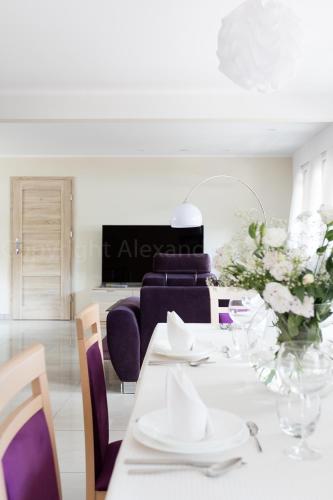 a dining room with a white table and purple chairs at Leśna Willa ŚWIT in Holendry