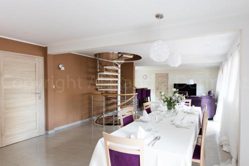 a dining room with a white table and a spiral staircase at Leśna Willa ŚWIT in Holendry