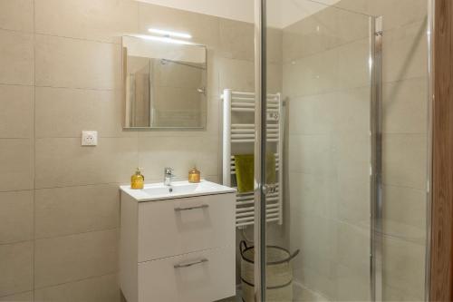 a white bathroom with a sink and a shower at Le Cocon d'Orezza - Appart Climatisé avec Balcon in Penta-di-Casinca
