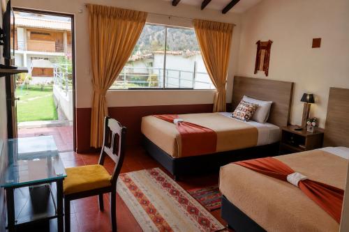 a hotel room with two beds and a table and a window at Chaska Valle Green in Urubamba