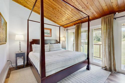 a bedroom with a canopy bed with a wooden ceiling at Griffin Chalet 5 in Stowe