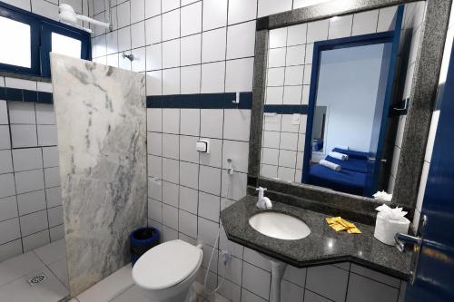 a bathroom with a toilet and a sink and a mirror at Pousada Villa Grécia in Aracaju