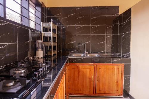 a kitchen with black tiled walls and a sink at Elikai Hostels 