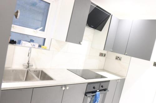 a kitchen with white cabinets and a sink and a window at Upton House in Chatham