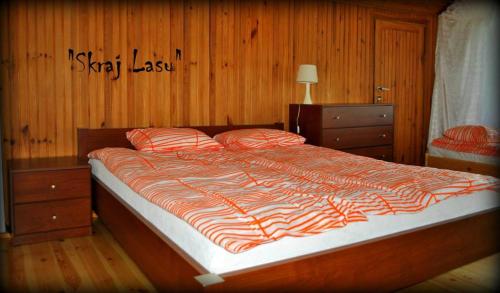 a large bed in a bedroom with wooden walls at Skraj Lasu Kruklanki in Kruklanki