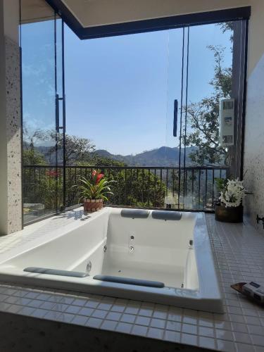 a white tub in a room with a large window at Loft Montclair in Nova Lima