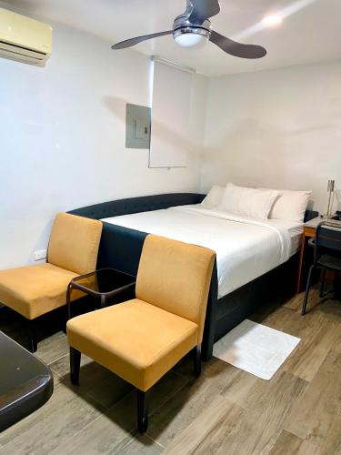 a bedroom with a bed and two chairs at The Ansen Place in Belmopan