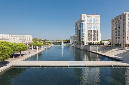a river in a city with tall buildings at Novotel Suites Montpellier Antigone in Montpellier