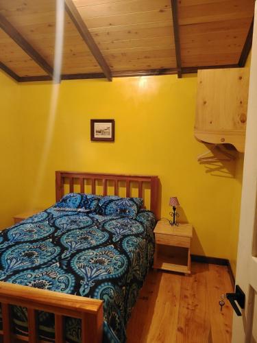 a bedroom with a bed in a yellow wall at Cabaña Santa Rosa in Tecpán Guatemala