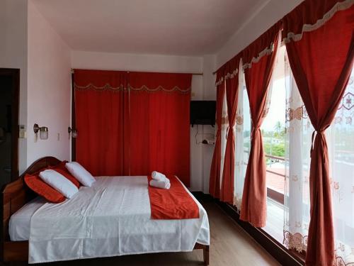 a bedroom with a bed with red curtains and a window at Vami's House in Puerto Villamil