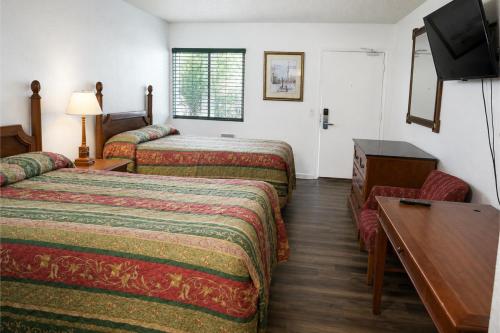 a hotel room with two beds and a flat screen tv at Solano Inn Vallejo Napa Valley - Six Flags in Vallejo