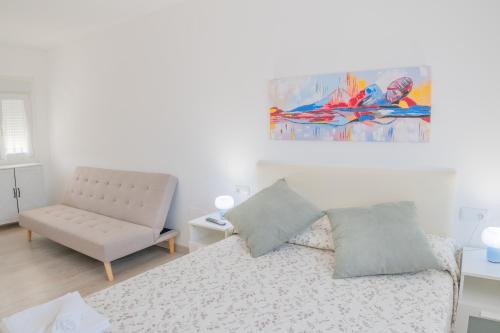 a white bedroom with a bed and a couch at Apartamento Aira in Villadepalos