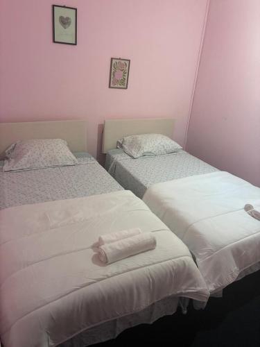two beds in a room with pink walls at Residencial Terminal Nunxá in Entroncamento
