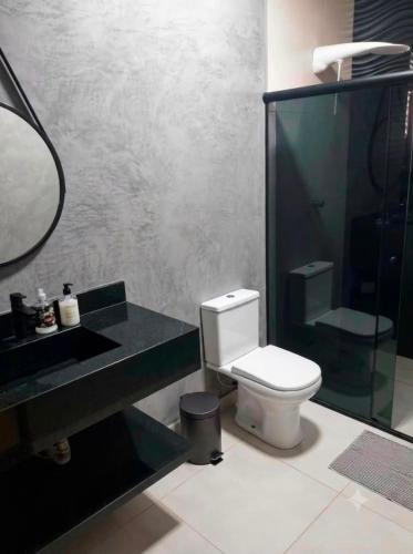 a bathroom with a toilet and a sink and a mirror at A Oca Praiana Suites in Ilha Comprida