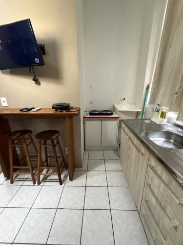 a kitchen with a sink and a desk with two stools at KITNETS Kretzer Hinckel 1 - CENTRO in Alfredo Wagner