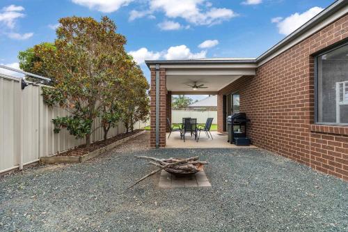 a backyard with a brick building and a patio at 28 Skye Ave - Skye High on Style in Moama