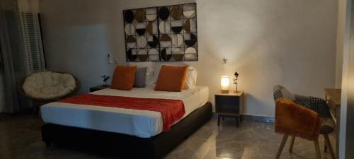 a bedroom with a bed with orange pillows on it at Kër Mouna MJN Hotels in Diass