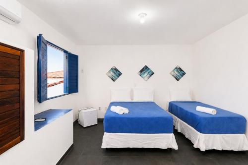 two beds in a white room with a window at Pousada Villa Grécia in Aracaju