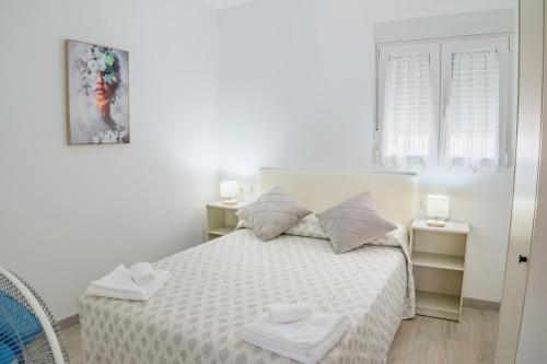 a white bedroom with a bed with two towels on it at Apartamento Aira 2 in Villadepalos