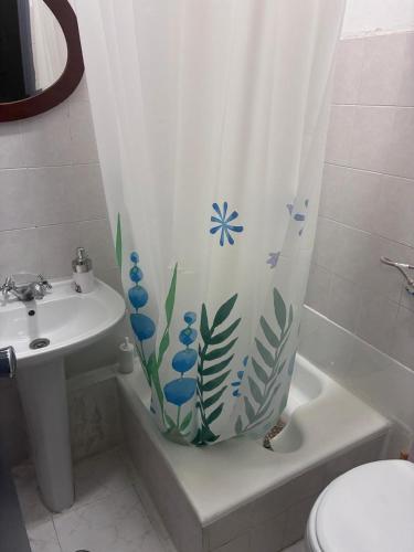 a bathroom with a shower curtain with blue flowers on it at Residencial Terminal Nunxá in Entroncamento