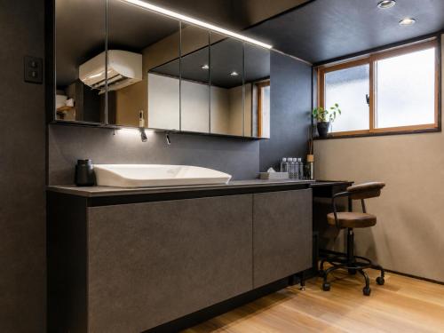 a bathroom with a sink and a counter with a stool at Jaune Chalet in Hakuba