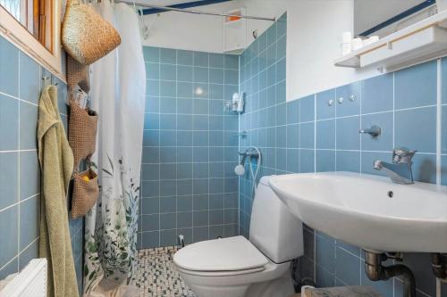 a blue tiled bathroom with a toilet and a sink at 2036-Stege-Solvgranen-16 in Stege