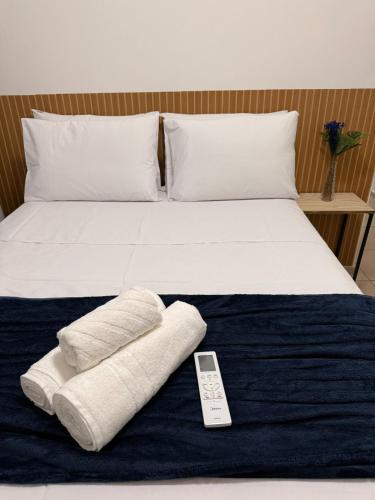a bed with two towels and a remote control on it at Spazio Cristalli Comfort in Cuiabá