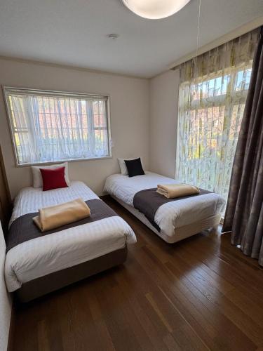 two beds in a room with two windows at Sea Shell Kawazu House in Kawazu