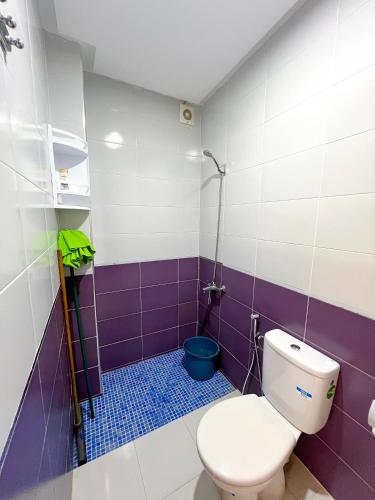 a bathroom with a toilet and purple and white tiles at Visit Chamal - Palmera 4 in Oued Laou