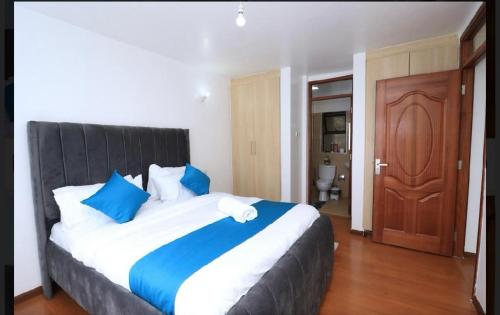 a bedroom with a large bed with blue and white pillows at Collins unique apartments in Ruaka