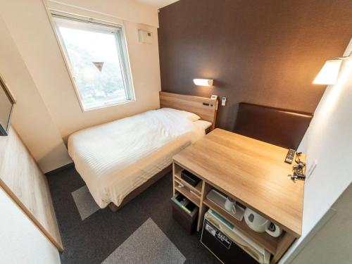 a small bedroom with a bed and a desk at Super Hotel Morioka in Morioka