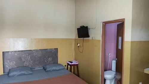 a bedroom with a bed and a toilet and a television at PONDOK CHILLY in Cirebon