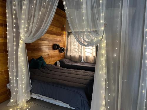 a bedroom with white curtains and a bed with a window at Refugio Viggena in Tandil