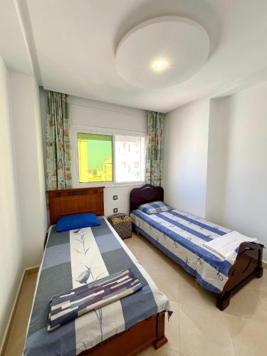 a bedroom with two beds and a window at Visit Chamal - Palmera 4 in Oued Laou