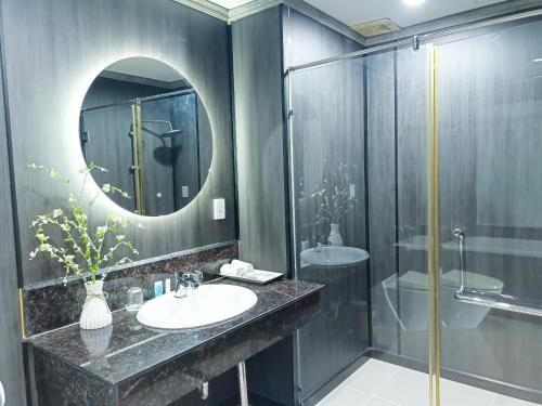 a bathroom with a sink and a shower and a mirror at River Hotel in Hà Tiên