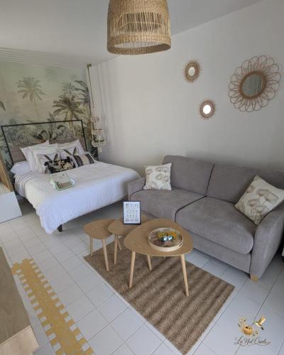 a living room with a couch and a bed at Le Nid Créole in Belle-Allée