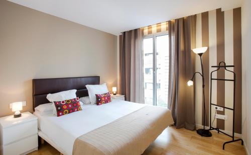ein Schlafzimmer mit einem weißen Bett und einem großen Fenster in der Unterkunft Durlet Beach Apartments in Barcelona