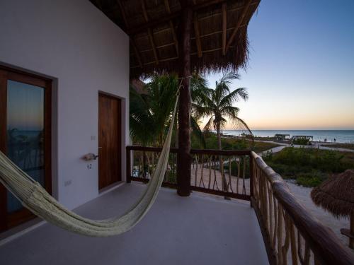 a room with a hammock on a balcony overlooking the beach at Villas HM Palapas del Mar in Holbox Island