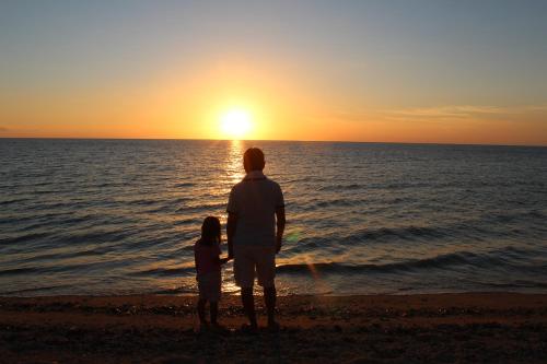 a man and a child standing on the beach watching the sunset at Seven Colors Ishigakijima in Ishigaki Island