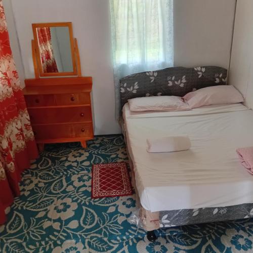 a bedroom with a bed and a dresser and a mirror at Pelly Homestay Adventure in Taveuni
