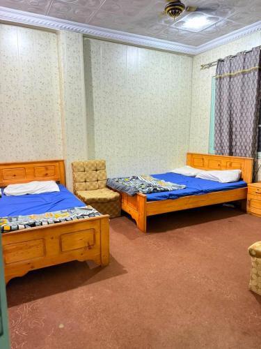 a room with two beds and a chair in it at Galiyat City hotel in Mingāora