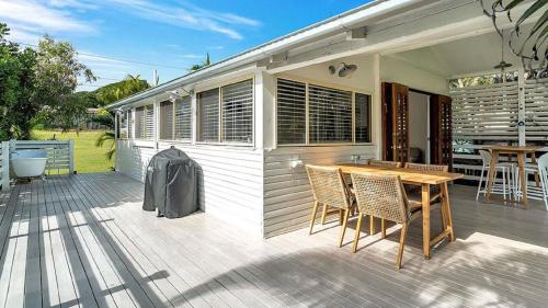 a deck with a wooden table and chairs on a house at Tullenderly in Wooli