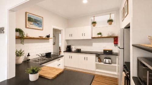 a kitchen with white cabinets and a sink at Surfside in Wooli