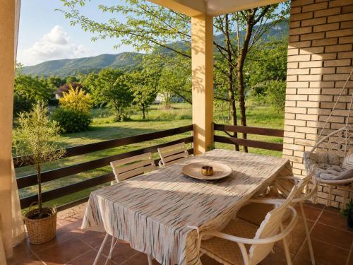 a wooden table and chairs on a porch with a view at Green Little Cottage with Pool near Ostrog Monastery in Danilovgrad
